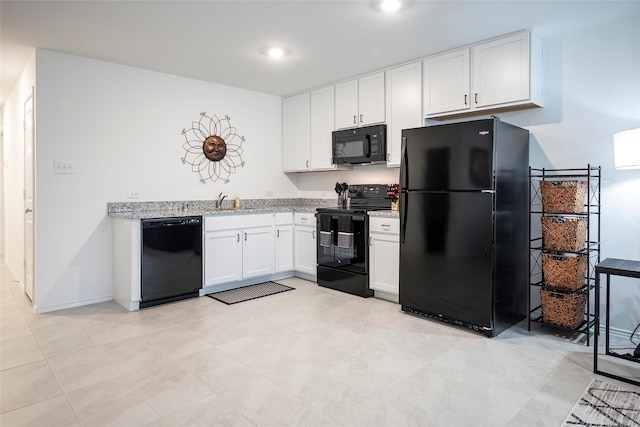 kitchen with light stone counters, white cabinets, sink, and black appliances