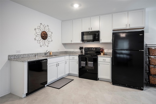 kitchen with white cabinetry, sink, light stone counters, and black appliances