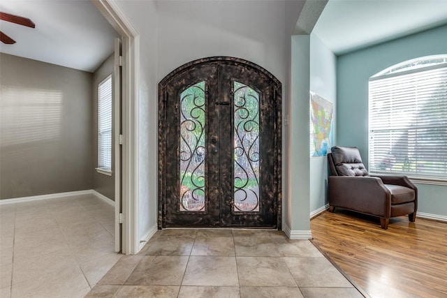 tiled foyer entrance with ceiling fan and french doors