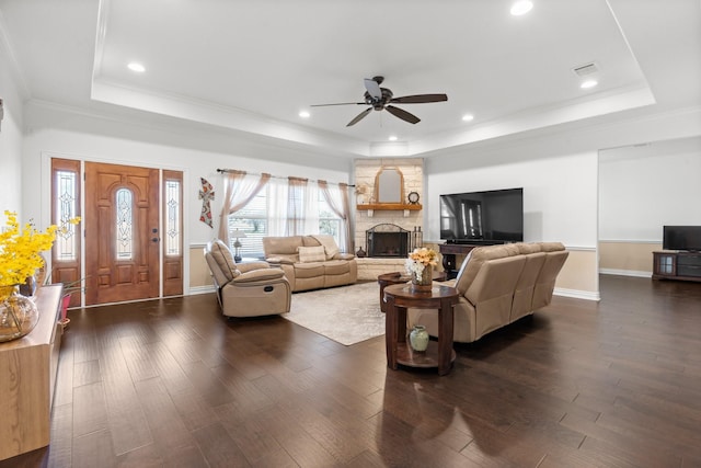 living room featuring ornamental molding, dark hardwood / wood-style floors, a fireplace, and a tray ceiling