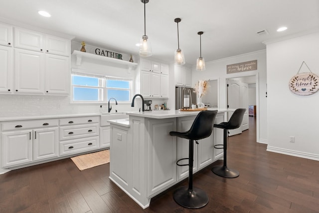 kitchen with hanging light fixtures, a center island, white cabinets, a kitchen bar, and high end refrigerator