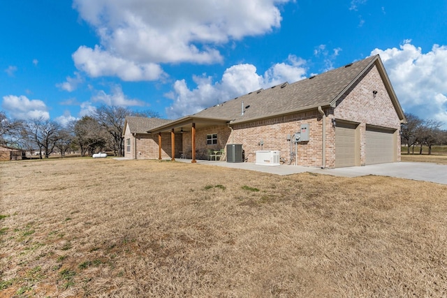 view of side of property with cooling unit, a garage, and a lawn