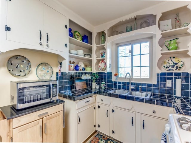 kitchen with white gas range, sink, tile countertops, and decorative backsplash