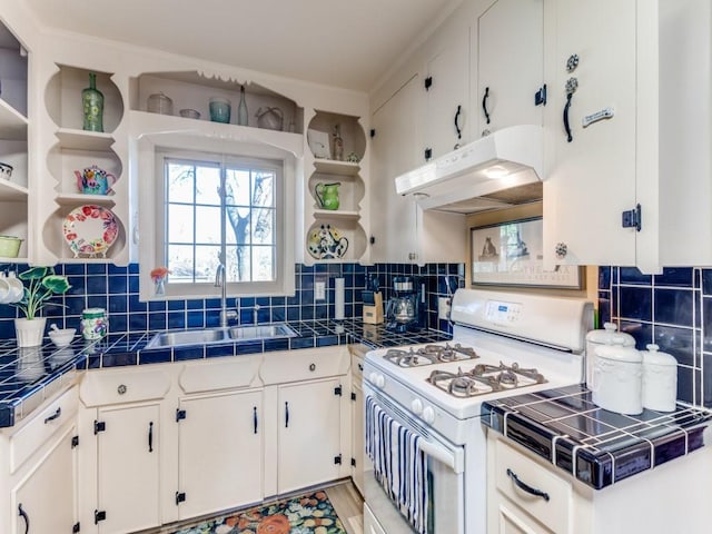 kitchen with white range with gas cooktop, sink, white cabinetry, and tile countertops