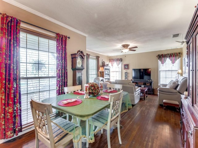 dining room featuring a textured ceiling, dark wood-type flooring, ornamental molding, and ceiling fan