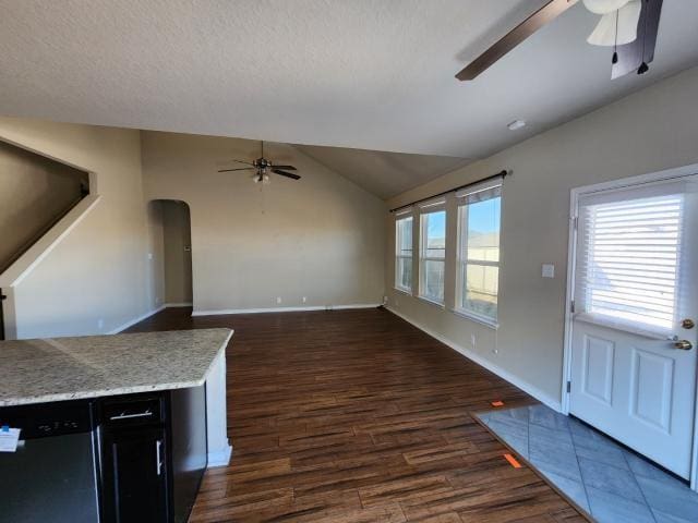 unfurnished living room featuring ceiling fan, dark hardwood / wood-style floors, vaulted ceiling, and a textured ceiling