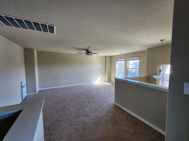 carpeted spare room featuring a textured ceiling and ceiling fan