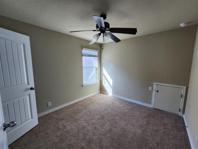 carpeted empty room with ceiling fan and a textured ceiling