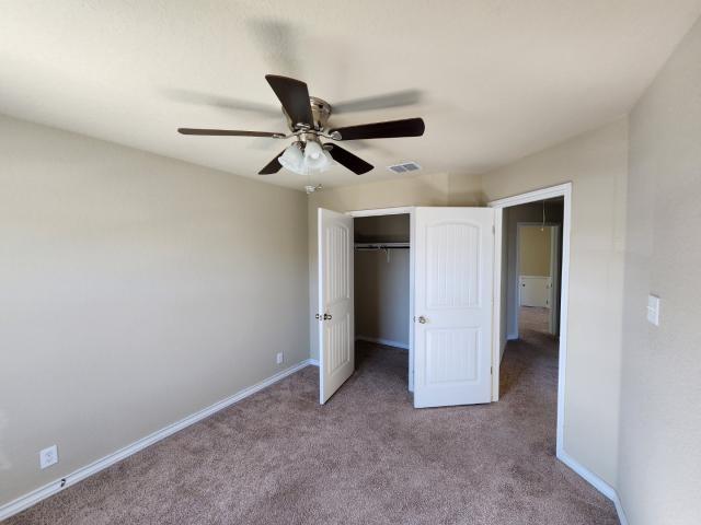 unfurnished bedroom with ceiling fan, light colored carpet, and a closet