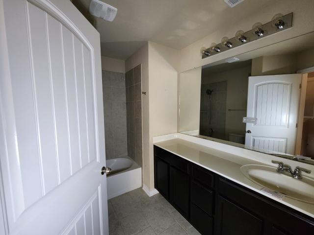 bathroom with vanity, tile patterned flooring, and tiled shower / bath