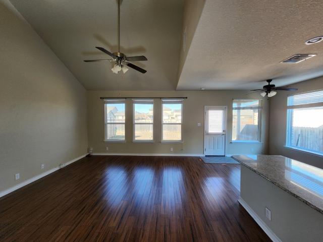 unfurnished living room with dark hardwood / wood-style flooring, ceiling fan, lofted ceiling, and a textured ceiling