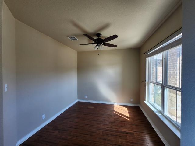 spare room featuring a textured ceiling, dark wood-type flooring, and ceiling fan