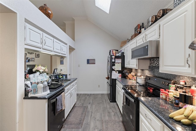 kitchen featuring white cabinetry, lofted ceiling with skylight, and black appliances