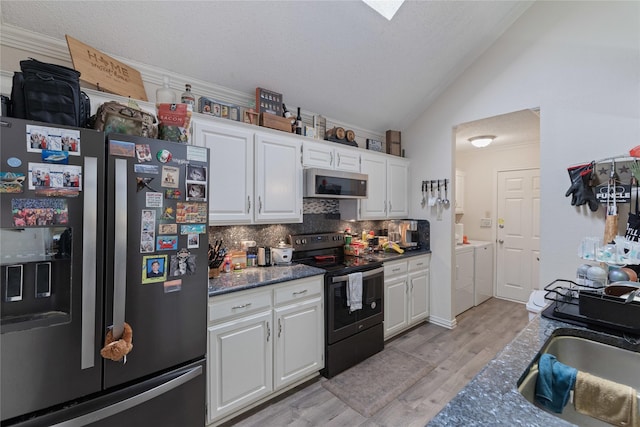 kitchen with vaulted ceiling, appliances with stainless steel finishes, white cabinetry, backsplash, and washing machine and clothes dryer