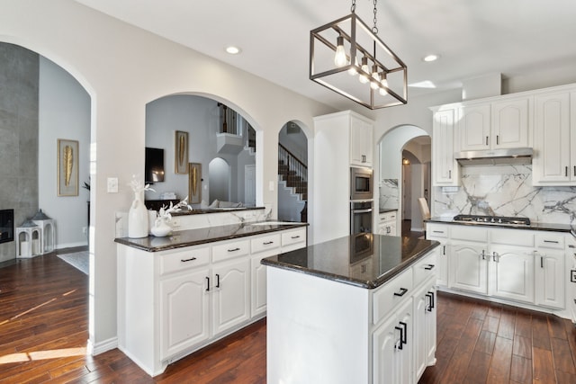 kitchen featuring white cabinetry, appliances with stainless steel finishes, a center island, and decorative light fixtures