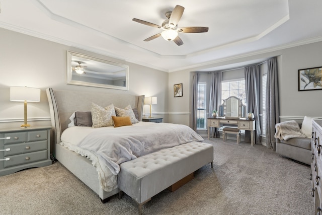 carpeted bedroom featuring a raised ceiling, ornamental molding, and ceiling fan