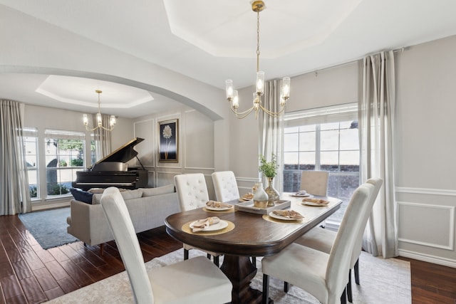 dining space featuring a raised ceiling, dark hardwood / wood-style floors, and a chandelier