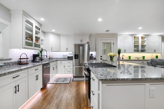 kitchen with stainless steel appliances, white cabinetry, a center island, and sink