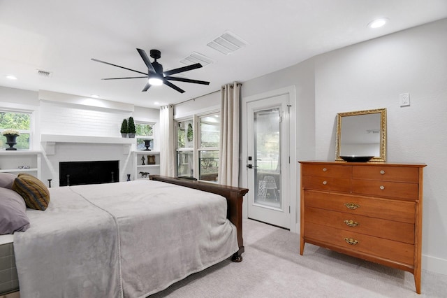 carpeted bedroom featuring multiple windows, access to exterior, a brick fireplace, and ceiling fan