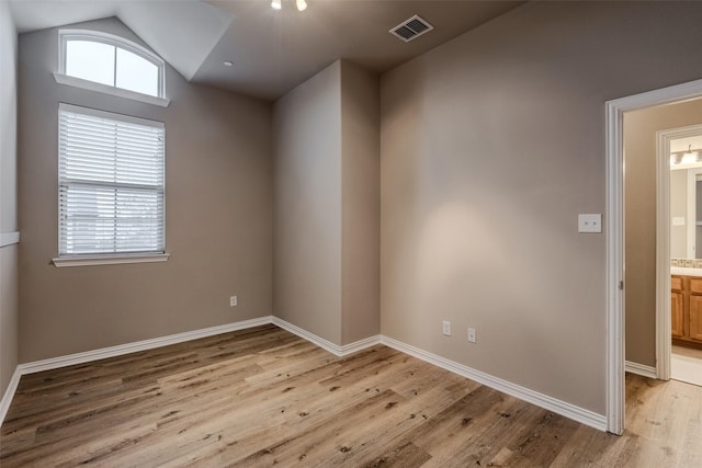 empty room with vaulted ceiling and light hardwood / wood-style floors