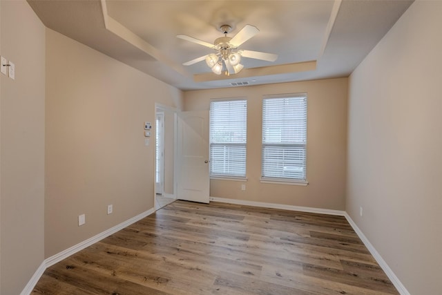 spare room featuring wood-type flooring, ceiling fan, and a tray ceiling