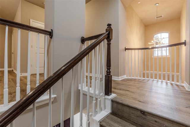 staircase with an inviting chandelier and hardwood / wood-style floors