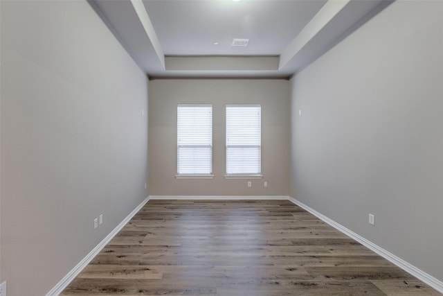 unfurnished room with hardwood / wood-style floors and a tray ceiling