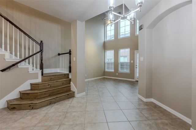 tiled entryway featuring an inviting chandelier and a towering ceiling