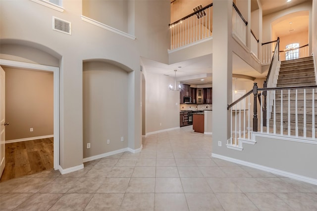 foyer entrance with a high ceiling, light tile patterned flooring, and an inviting chandelier