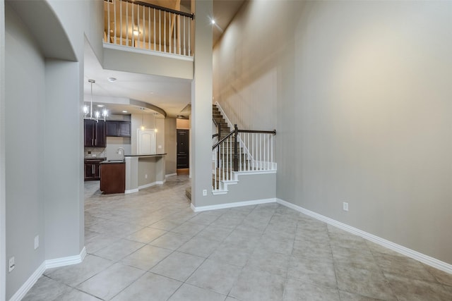 tiled foyer entrance with a towering ceiling, sink, and an inviting chandelier