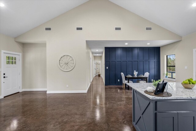 kitchen featuring light stone counters and high vaulted ceiling