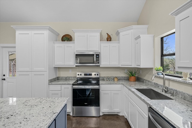 kitchen featuring vaulted ceiling, sink, white cabinets, stainless steel appliances, and light stone countertops