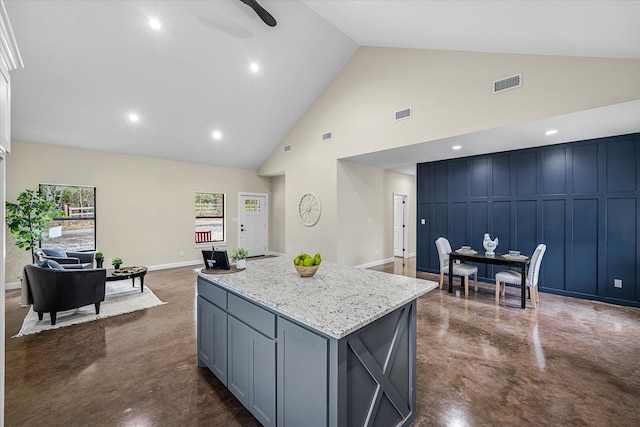 kitchen with gray cabinets, light stone countertops, high vaulted ceiling, and a kitchen island