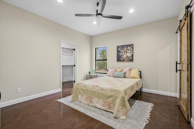 bedroom featuring ceiling fan, a barn door, a closet, and a spacious closet