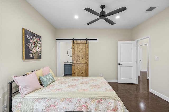 bedroom featuring ceiling fan, connected bathroom, and a barn door