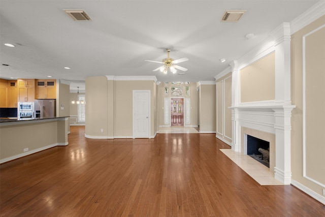 unfurnished living room featuring wood-type flooring, ornamental molding, ceiling fan, and a high end fireplace