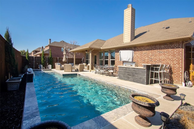 view of swimming pool with a bar, pool water feature, and a patio area