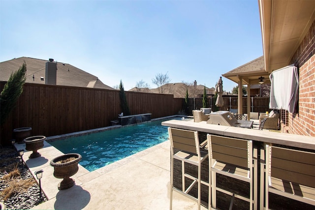 view of swimming pool featuring a patio, exterior bar, area for grilling, and pool water feature