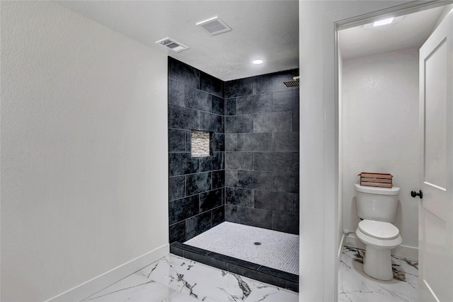 bathroom with tiled shower, a textured ceiling, and toilet