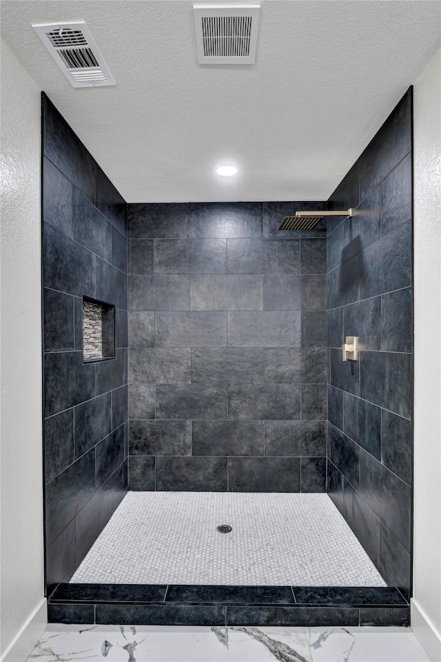 bathroom with tiled shower and a textured ceiling