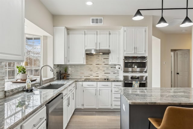 kitchen with stainless steel appliances, backsplash, a sink, and under cabinet range hood