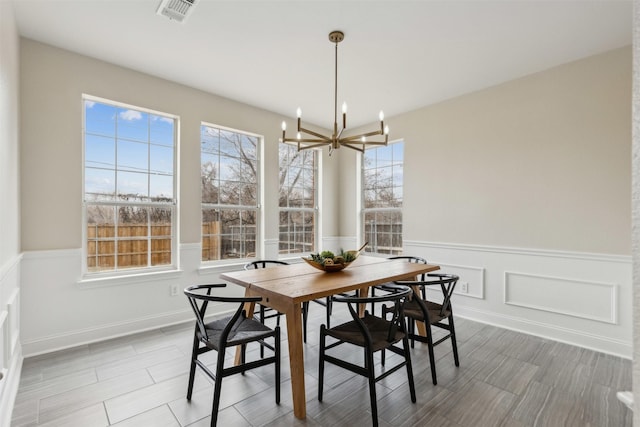 dining area featuring visible vents, a chandelier, and wainscoting