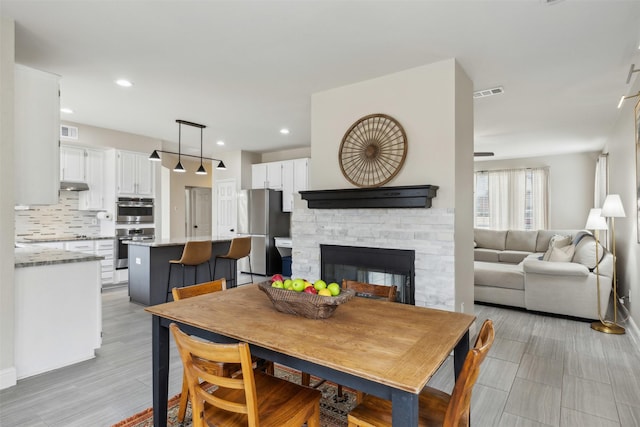 dining area featuring recessed lighting, visible vents, and a stone fireplace