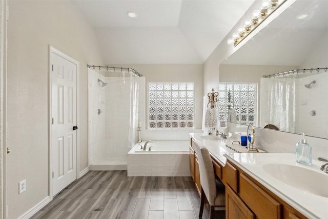 bathroom with vaulted ceiling, a sink, a garden tub, and a tile shower