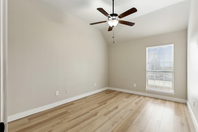 spare room featuring lofted ceiling, light wood-type flooring, a ceiling fan, and baseboards