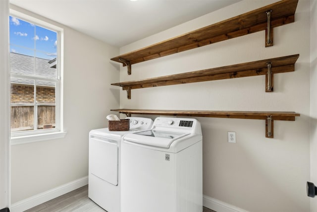 laundry area featuring light wood-style floors, plenty of natural light, baseboards, and washer and dryer