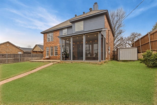 back of house with a lawn, a chimney, a fenced backyard, and a sunroom