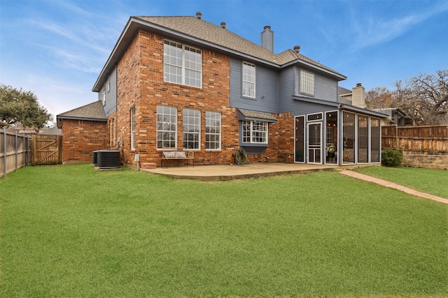 back of property featuring a sunroom, a fenced backyard, a chimney, a patio area, and brick siding