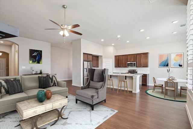 living area featuring ceiling fan, arched walkways, baseboards, dark wood-type flooring, and visible vents