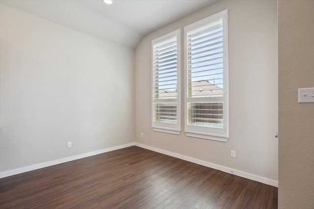 unfurnished room featuring baseboards, dark wood finished floors, and lofted ceiling
